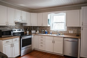 Updated kitchen with stainless steel appliances, cookware, and dining ware