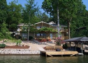 View of the house from the lake, with swimming dock and fire pit