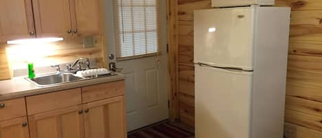 Kitchenette with refrigerator, microwave, dishes, and utensils. 