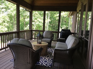 Spacious overed porch with sofa and swivel chairs.