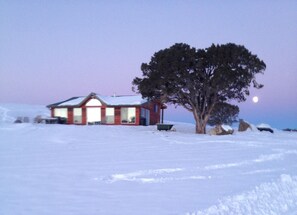 As the moon sets, the sun rises over the Ranch and is reflected in the windows.