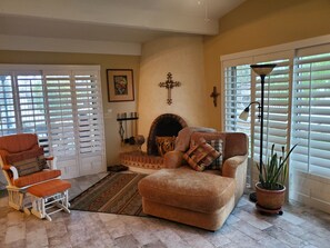 Arizona room with chaise lounge and recliner, and decorative fireplace.