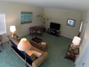 living room has a big screen TV, a futon couch that makes into a Queen bed plus