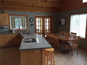 Kitchen eating island and table with doors into the sunroom