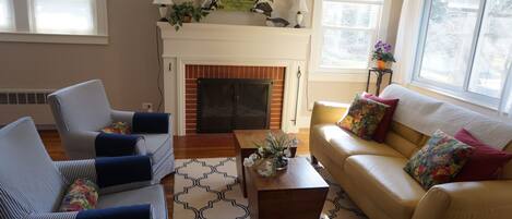 Living room with wood burning fireplace. Opposite wall is flatscreen TV. 