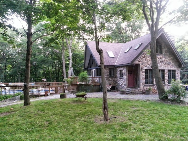 Stone house on a countryside setting with fenced in deck and seasonal pool