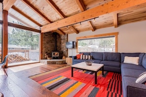 Large windows open up onto a sunny deck with expansive mountain views.