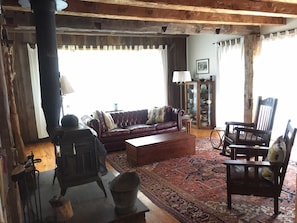Romantic living room with leather couch, wood stove and french doors onto deck