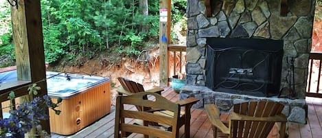 Outside fireplace (firewood provided), dining table, and hot tub.