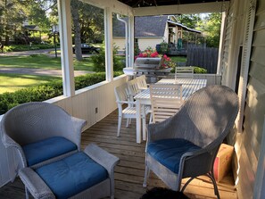Screened in front porch with grill, dining table and sitting area.
