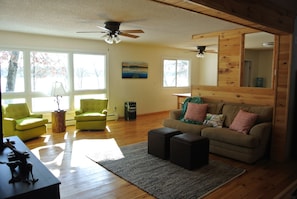 Living area with TV and generous windows opens to the spacious kitchen