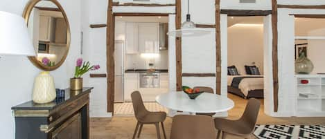 Dining area with kitchen and bedroom in the background.