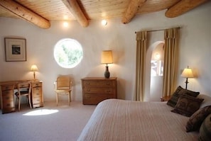 Upstairs bedroom, rounded walls, vigas, large windows facing mountains, king bed