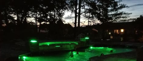 night time view of pool and tanning ledge