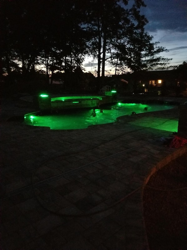 night time view of pool and tanning ledge