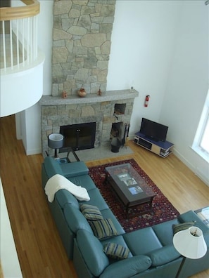 Maine-modern interior with custom fireplace. Upstairs balcony/sunroom visible.