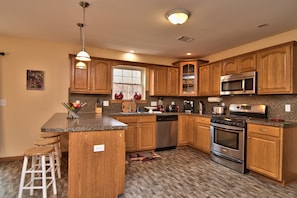 Across is the gourmet kitchen with stainless steel appliances and breakfast bar