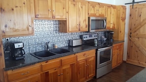 Knotty pine kitchen with new stove and microwave, bar door leads to foyer