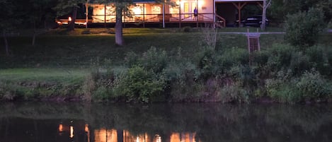 The cabin reflects in the New River as night settles in.