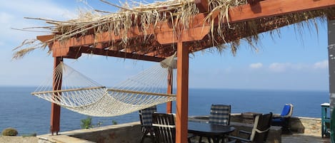 Covered veranda with sea view, hammock and dining table, coffee table, loungers