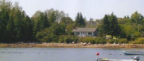 46 School St. from the water showing house, decks, woods, lawn, shoreline, steps