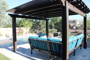 Very comfortable sofa and chairs under a pergola providing cool shade