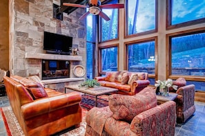 Bright and airy living room with expansive windows offering breathtaking mountain views, providing a perfect setting for relaxation and entertainment.
