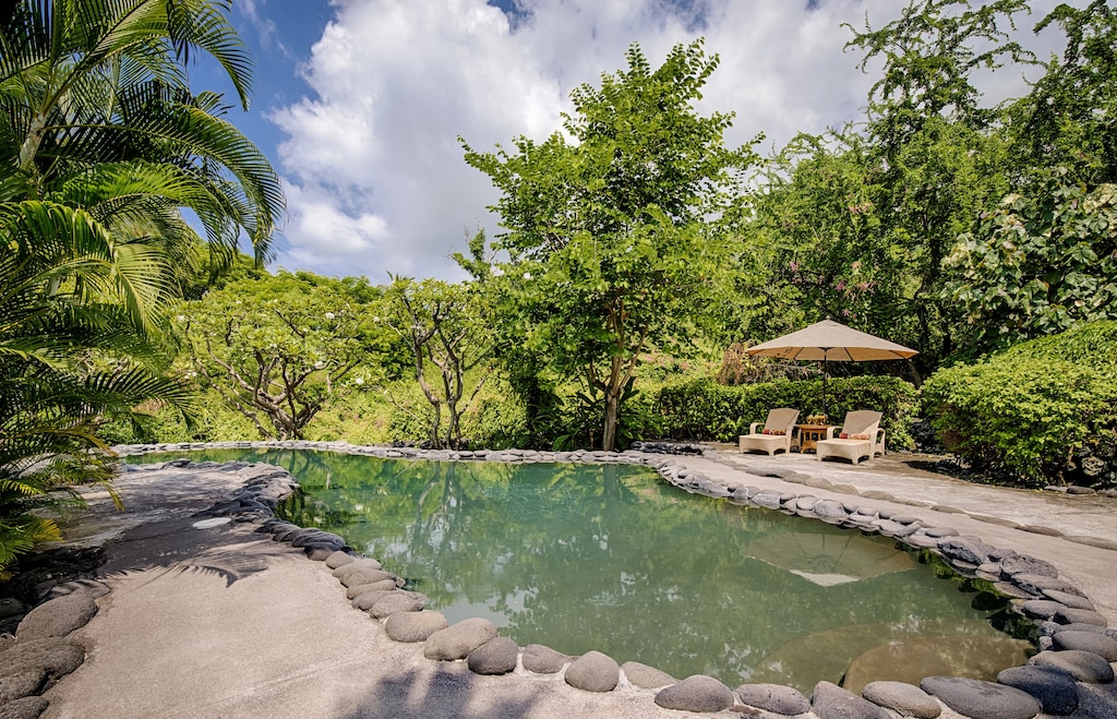 Lagoon pool and lounge chairs in a tropical setting can be rented on VRBO Kona Hawaii Big Island
