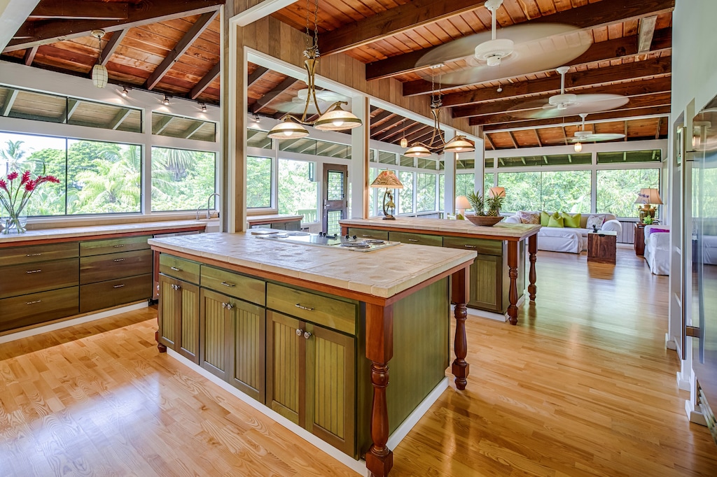 Kitchen in a wooden interior with open windows overlooking lush foliage