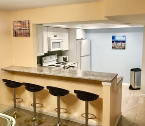 Newly remodeled and fully stocked kitchen, with breakfast bar. 