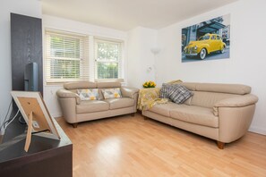 Bright living area with comfortable leather sofas, dining table & TV