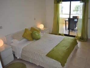 Master bedroom with en-suite bathroom, kingsize bed and balcony overlooking the pool