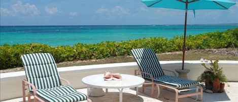 Oceanfront patio with 4 chaise lounges and round table with 4 chairs