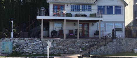 House from the water. Sun and shaded seating. Gas fire pit w/ chairs on the left