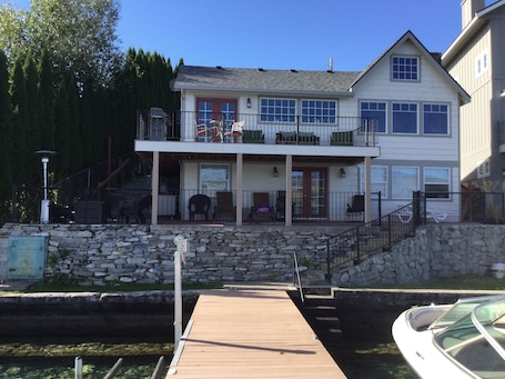 House from the water. Sun and shaded seating. Gas fire pit w/ chairs on the left