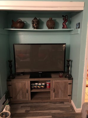 50" TV with supplies beneath including French Market coffee and cups