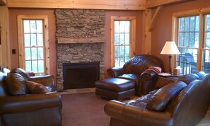 Great room with pine flooring, authentic fireplace, and leather furniture.