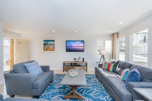 Open up the front door into the main living area, which includes a sofa/loveseat set, side seating, cable TV, and a sliding glass door that opens to expansive front ocean view patio.
                