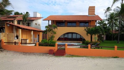 Casa de praia com piscina, terraço e pé na areia.