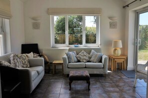 Living room with large doors to patio and garden. Wheelchair accessible.


