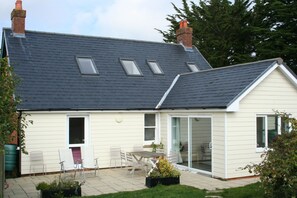 Eastern Lee from back garden. Patio with wide entry doors to living room.
