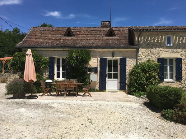 The front of the gite with travertine patio and patio set with sun umbrella