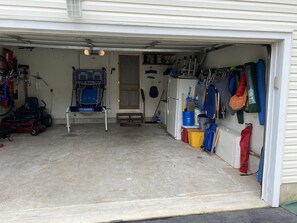 Garage loaded with chairs, umbrellas and bikes.  There's even a basketball game