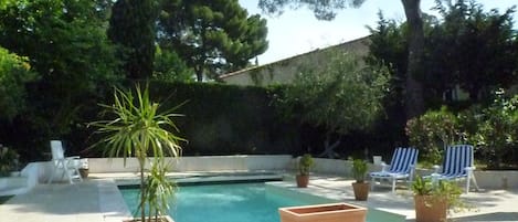 Piscine entourée de terrasses et de verdure.