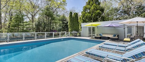 huge swimming pool and deck surrounded by trees

