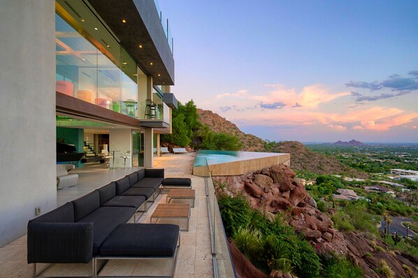 Luxury outdoor couch near pool with panoramic doors to the inside 