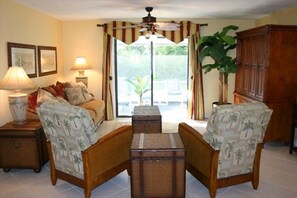 Tropic themed living room looking out onto the lanai and armoire for large TV.