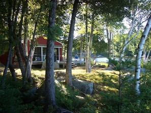 Front of cottage w/sunny deck,chairs,grill,shaded hammock in the trees,fire pit.