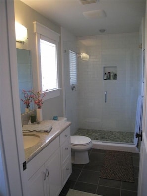 Bathroom, walk in shower, pebble tile floor, luxurious linens.