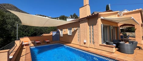 Poolterrasse mit Sonnensegel und angrenzender Lounge 